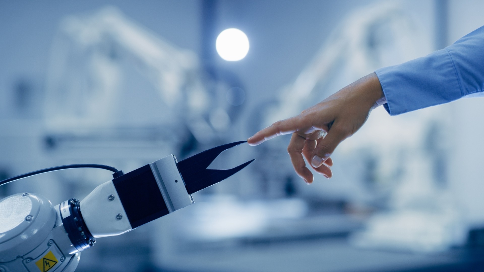 Creation, tech or automation with a hand and robot arm in an industry 4.0 factory for futuristic design. Robotics, innovation or ai with human and machine in collaboration for warehouse production